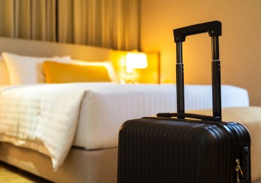 Luggage at the forefront of a bed in a hotel room